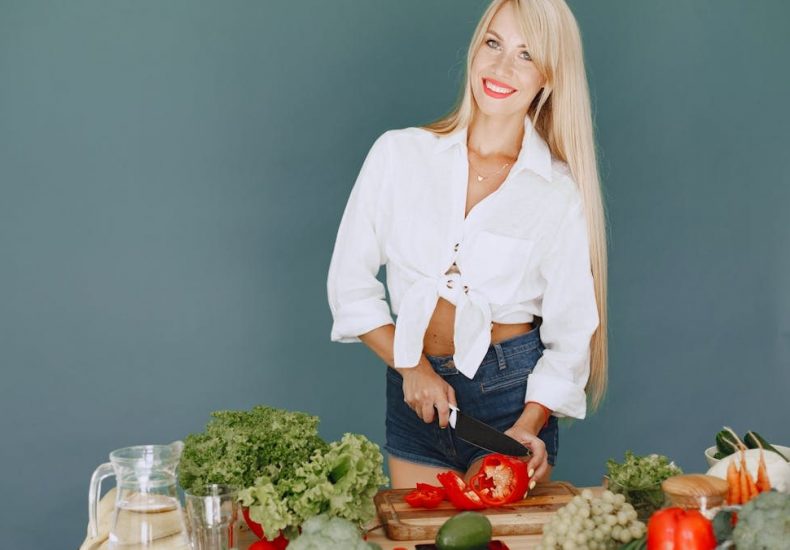 A smiling blonde woman chops vegetables, promoting healthy eating and lifestyle.