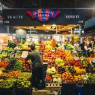 Colorful market stall displaying fresh fruits and vegetables in Barcelona's bustling market.