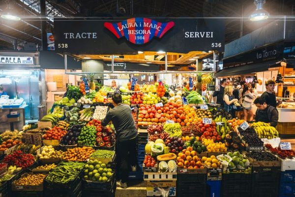 Colorful market stall displaying fresh fruits and vegetables in Barcelona's bustling market.
