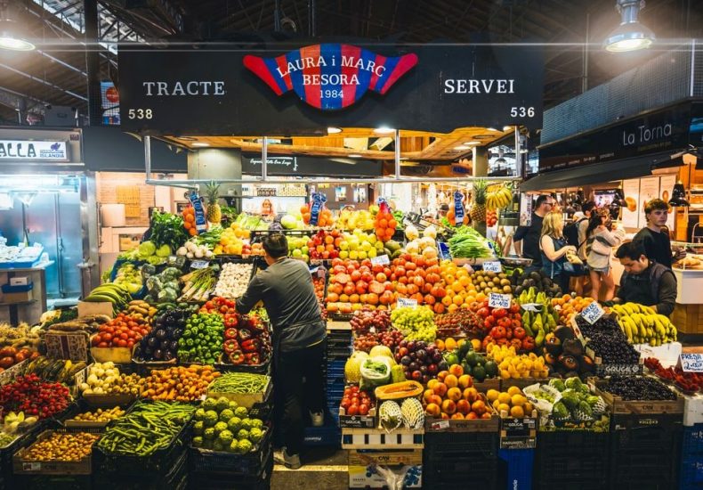 Colorful market stall displaying fresh fruits and vegetables in Barcelona's bustling market.