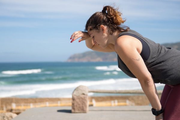 A woman rests after exercise, overlooking the ocean in Portugal's scenic seascape.